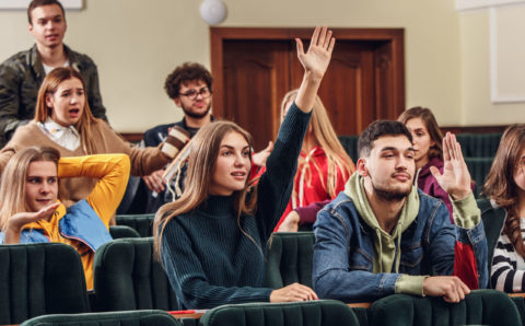 The group of cheerful happy students sitting in a lecture hall before lesson