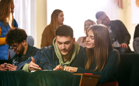 The group of cheerful happy students sitting in a lecture hall before lesson